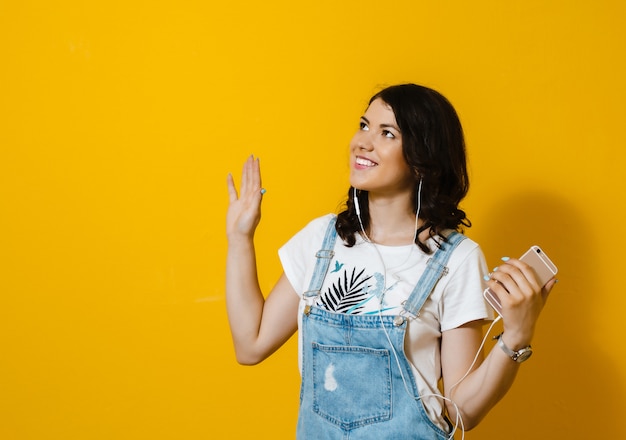 Imagem de mulher feliz usando fones de ouvido cantando isolado sobre parede amarela