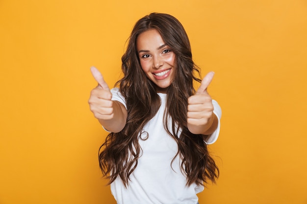 Imagem de mulher jovem feliz isolada sobre a parede amarela, mostrando os polegares para cima gesto.