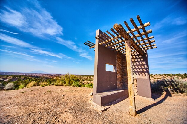 Imagem de pequena estrutura de assento de madeira e gesso no deserto com areia e céu azul