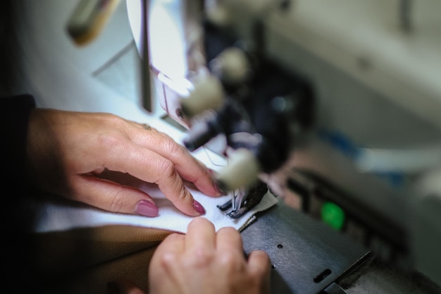 Imagem de perto de uma mulher operando uma máquina de costura industrial