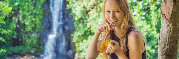 Imagem de retrato aproximada de uma linda mulher bebendo chá gelado sentindo-se feliz na natureza verde e