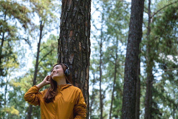 Imagem de retrato de uma bela jovem asiática gosta de ouvir música com fone de ouvido no parque