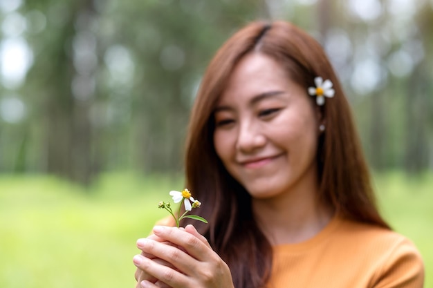 Imagem de retrato de uma bela jovem asiática segurando Biden Alba ou flor de agulhas espanholas no parque