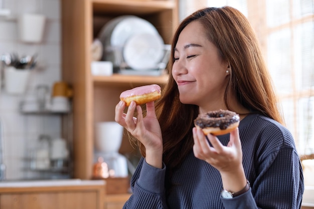 Imagem de retrato de uma bela jovem asiática segurando e gostava de comer rosquinhas em casa