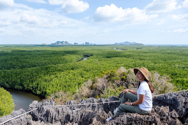 Imagem de retrato de uma bela jovem asiática sentada no pico da montanha enquanto viajava pelo ponto de vista da floresta de mangue