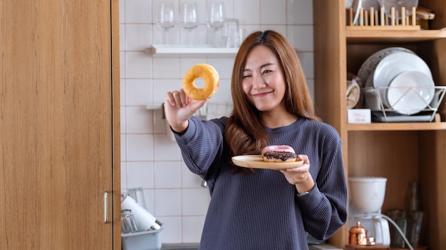 Imagem de retrato de uma jovem asiática segurando e olhando através de buracos de donuts na cozinha em casa