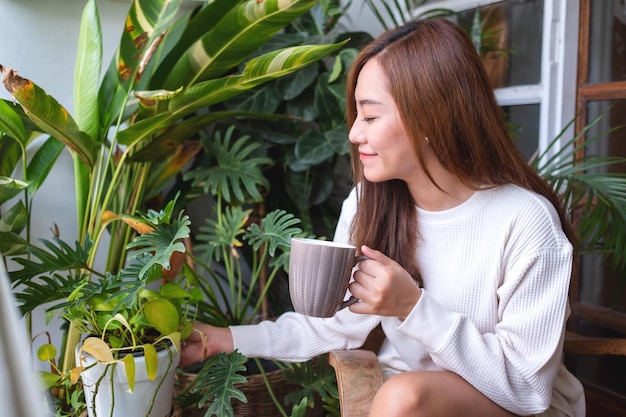 Imagem de retrato de uma linda mulher asiática bebendo café quente e cuidando do jardim de plantas de casa na varanda em casa