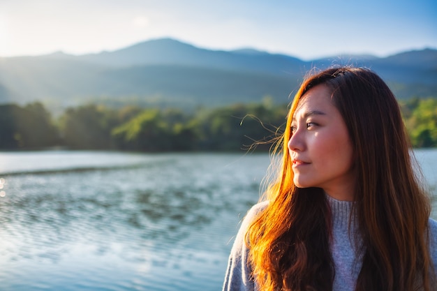 Foto imagem de retrato de uma linda mulher asiática em frente ao lago e às montanhas antes do anoitecer