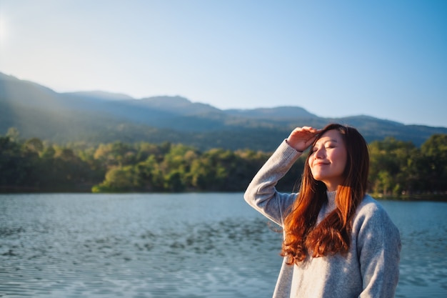 Foto imagem de retrato de uma linda mulher asiática em frente ao lago e às montanhas em um dia ensolarado