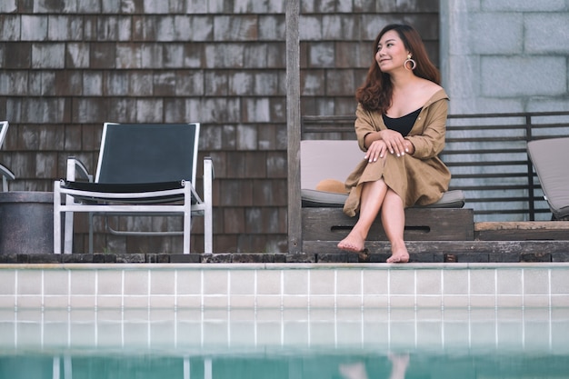 Imagem de retrato de uma linda mulher asiática gostando de sentar à beira da piscina