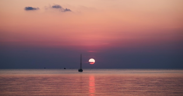 Imagem de silhueta de um belo pôr do sol no mar com barco a vela