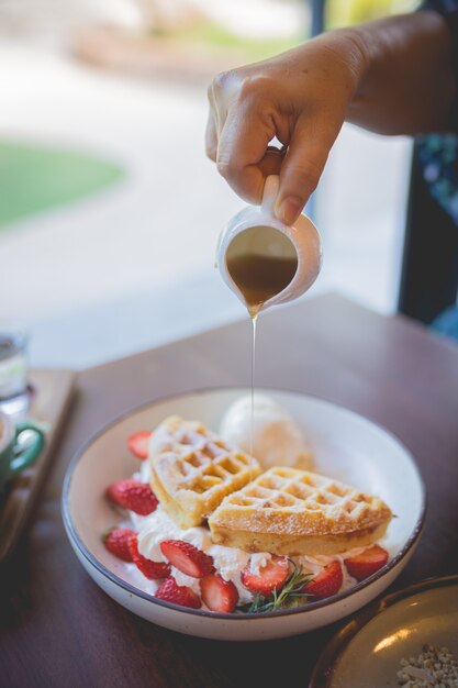 Imagem de sobremesa de panqueca de waffle com sorvete de baunilha, morango fresco e calda de mel