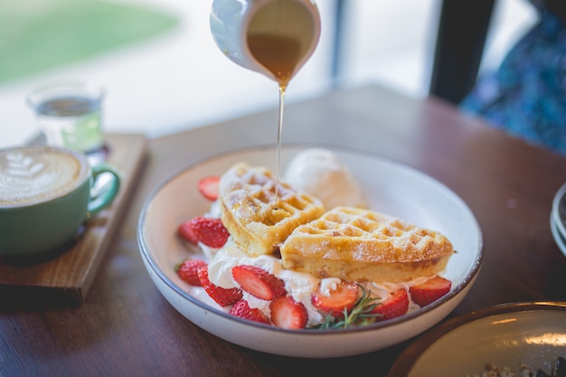 Imagem de sobremesa de panqueca de waffle com sorvete de baunilha, morango fresco e calda de mel