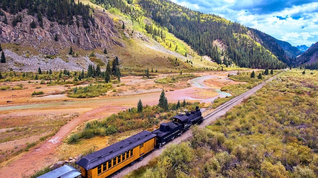 Imagem de trem vintage com carvão conduzindo passageiros ao longo do vale nas montanhas ao longo do rio