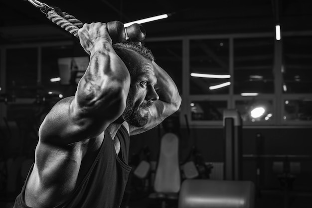 Imagem de um atleta poderoso se exercitando em um crossover na academia. Bombeamento de tríceps. Conceito de fitness e musculação. Mídia mista