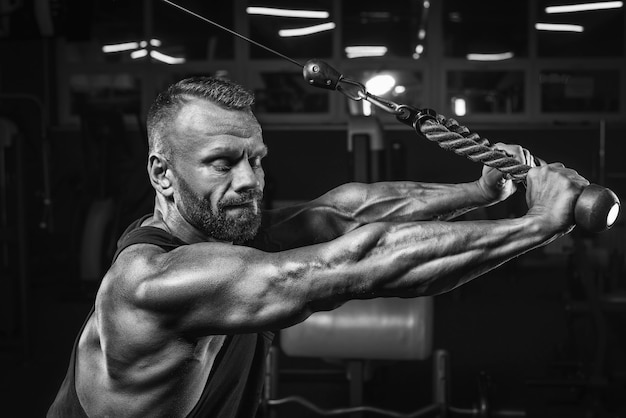 Imagem de um atleta poderoso se exercitando em um crossover na academia. bombeamento de tríceps. conceito de fitness e musculação. mídia mista