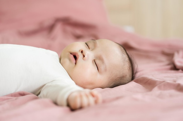 Imagem de um bebê recém-nascido deitado em uma cama rosa
