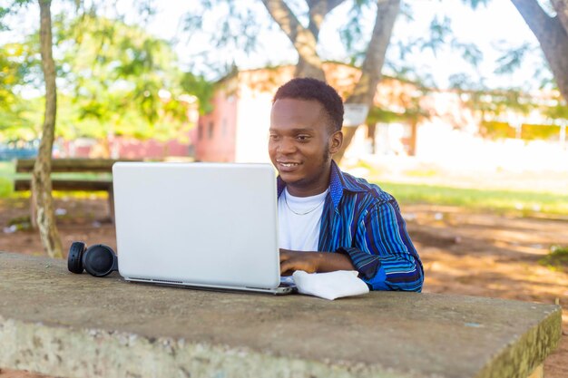 imagem de um belo estudante africano centralizado usando laptop no ambiente do campus da escola