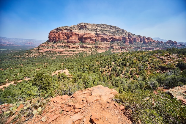 Imagem de um grande afloramento rochoso multicolorido elevando-se sobre árvores verdes Devils Bridge