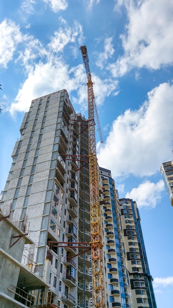 Imagem de um guindaste alto no canteiro de obras do novo distrito moderno contra o céu azul com nuvens brancas