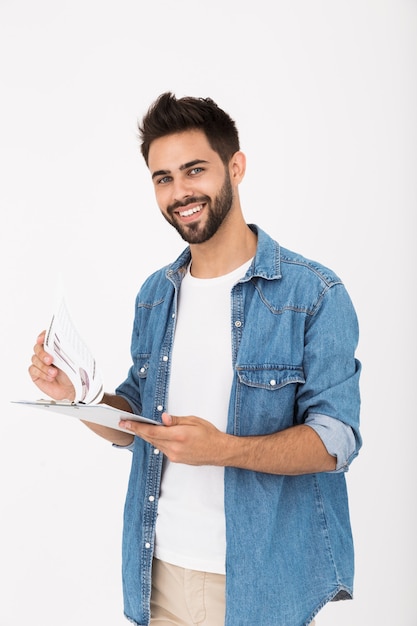 Imagem de um homem bonito e feliz segurando uma prancheta com infográficos e sorrindo isolada na parede branca