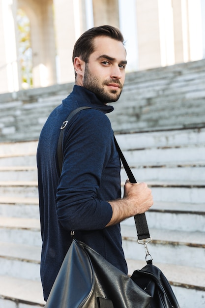 Imagem de um homem bonito sério jovem esportes fortes posando ao ar livre no saco de exploração de localização do parque natural.