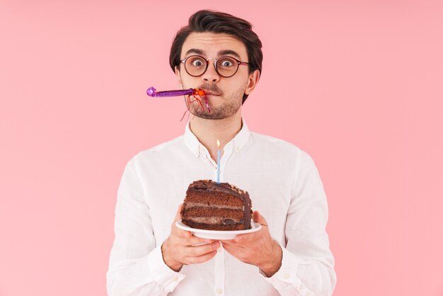 Foto imagem de um homem caucasiano surpreso usando óculos e segurando um bolo de chocolate com uma vela isolada