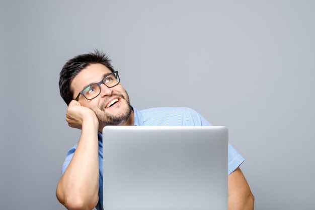 Foto imagem de um homem pensativo vestido com uma camisa azul usando um computador portátil