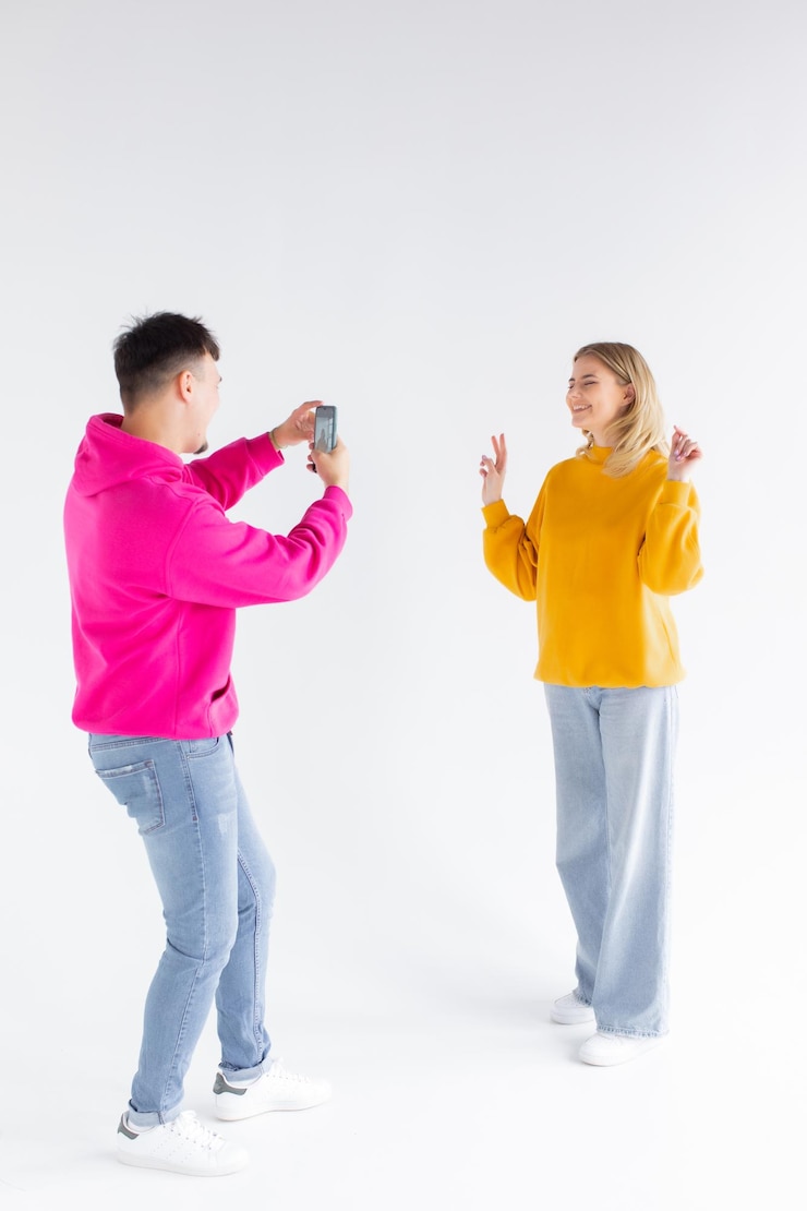 Imagem de um homem tira foto de sua mulher otimista positiva em fundo branco por telefone celular