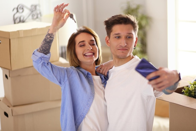 Imagem de um jovem casal feliz se abraçando enquanto o homem mostrava a chave do novo apartamento