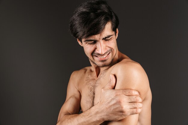 Imagem de um jovem triste descontente com dor no braço posando isolado.