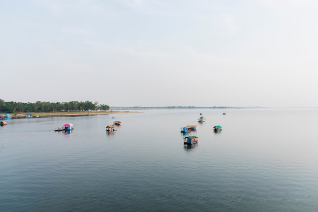 Imagem de um pequeno barco e uma jangada flutuando na água em um reservatório.