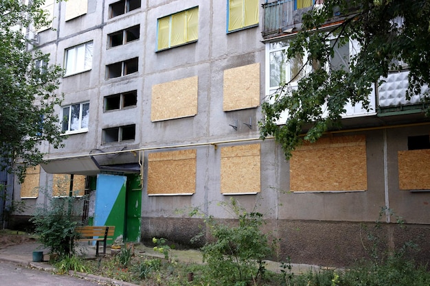 Imagem de um prédio residencial alto no qual as janelas são protegidas de possíveis bombardeios por madeira compensada