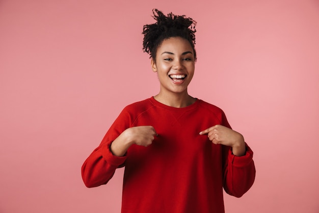 Imagem de uma bela jovem animado feliz emocional mulher africana posando sobre parede rosa, apontando para si mesma.