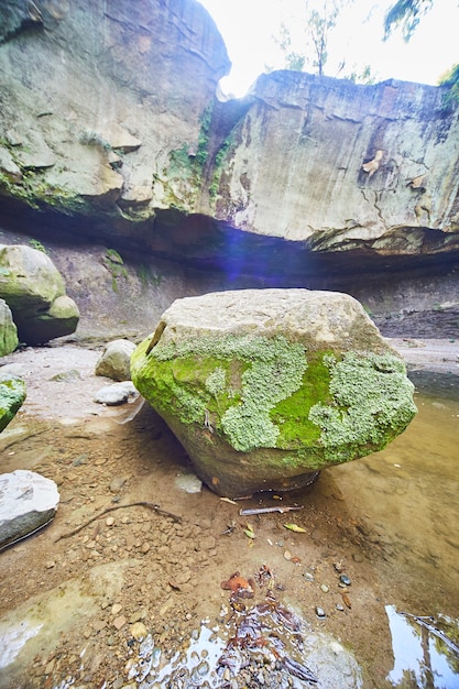 Imagem de uma grande pedra com musgo dentro de uma bacia de cachoeira seca