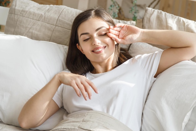 Imagem de uma jovem bonita sorridente deitada na cama dentro de casa