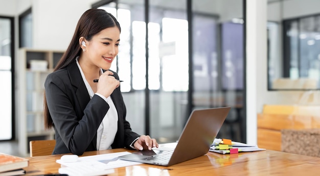 Imagem de uma jovem e linda empresária alegre sorrindo enquanto trabalhava com laptop no escritório