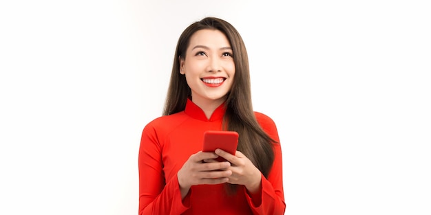 Imagem de uma jovem feliz em vestido tradicional vietnamita conversando por telefone de pé isolada sobre branco Olhando para um lado