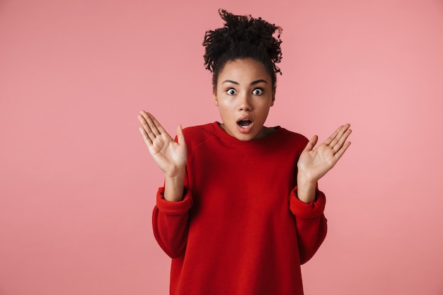 Imagem de uma linda mulher africana chocada jovem incrível posando sobre parede rosa.