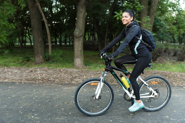 Imagem de uma linda mulher andando de bicicleta no parque ao ar livre.