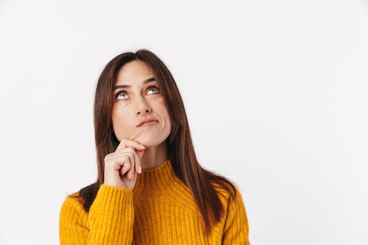Foto imagem de uma linda mulher morena adulta vestindo um suéter pensando e olhando para cima em copyspace isolado no branco