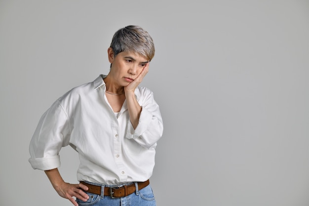 Imagem de uma mulher asiática de meia-idade, confusa e intrigada, isolada sobre um fundo branco