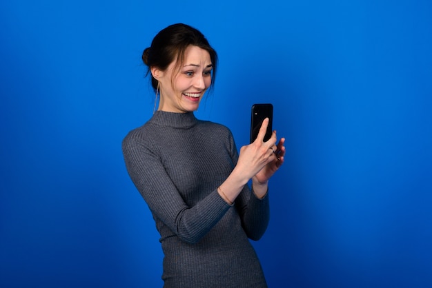 Imagem de uma mulher bonita jovem chocada surpresa feliz posando isolado sobre fundo azul