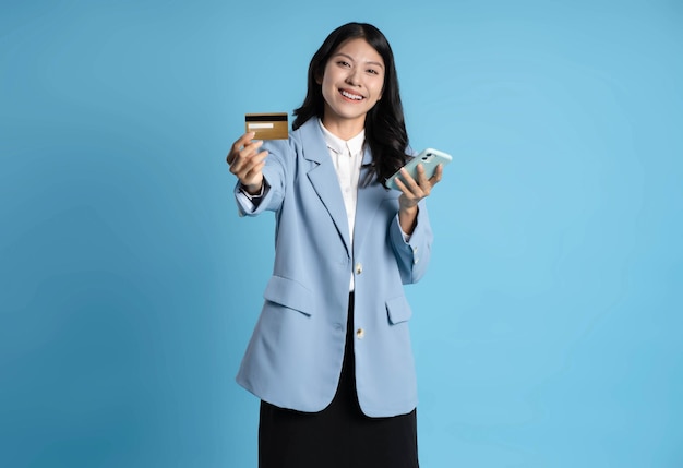 imagem de uma mulher de negócios asiática segurando um cartão bancário em um fundo azul