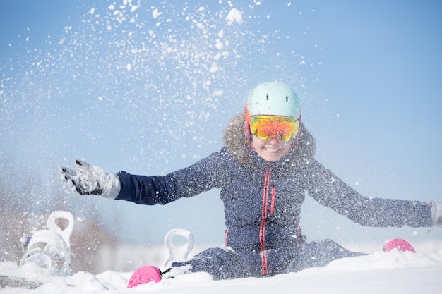 Imagem de uma mulher esportiva sentada em um monte de neve jogando neve