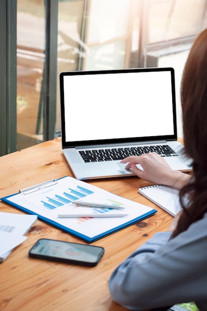 Imagem de visão vertical da mão de uma mulher usando um computador laptop com uma tela em branco enquanto está sentado à mesa.