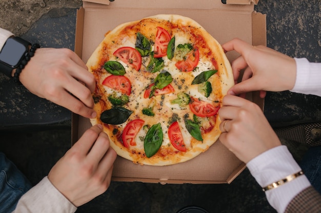 Imagem de vista superior de casal pegando fatias de pizza da caixa ao ar livre