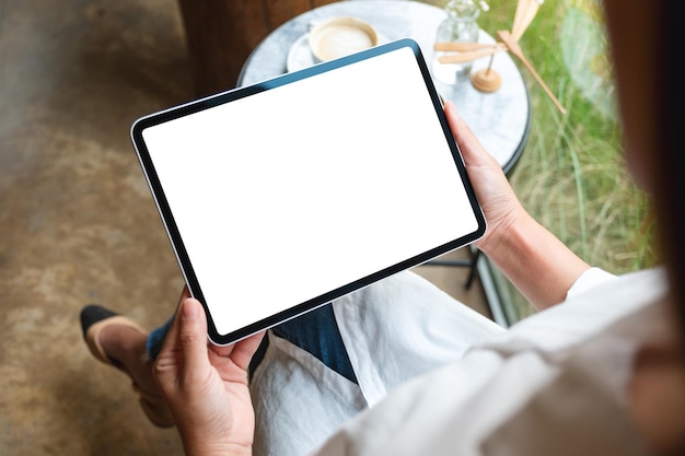 Imagem de vista superior de uma mulher segurando tablet digital com tela branca em branco no café