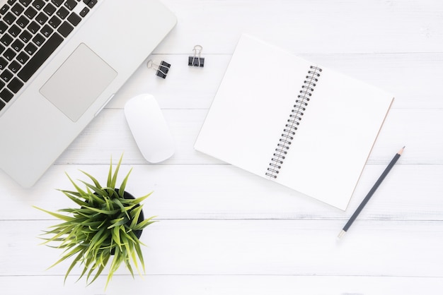 Imagem de vista superior do caderno aberto com páginas em branco e laptop na mesa de madeira