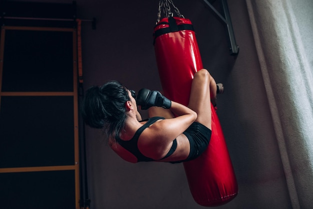 Imagem de vista traseira do boxeador jovem batendo um enorme saco de pancadas em um estúdio de boxe Kickboxer desportista treinando duro na academia Estilo de vida esportivo e conceito de pessoas